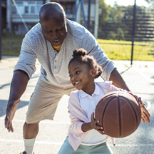 child and grandparent playing basketball outside